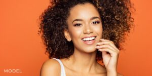 Smiling Teen Model Against Orange Background | Mercer Island Oral Maxillofacial Surgery A teen model demonstrates the potential results of wisdom teeth removal